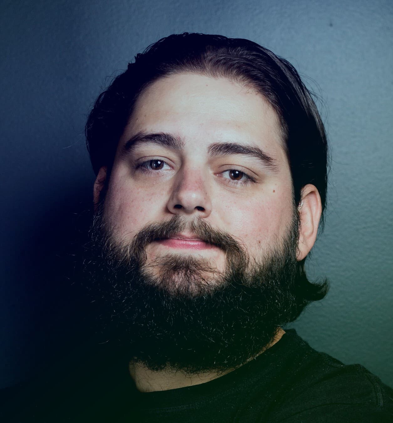 Kaue faces posing with black shirt and blueish background